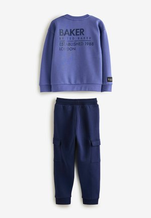 Purple sweatshirt with “BAKER” text on the back, paired with navy joggers featuring side pockets and ribbed cuffs. Soft fabric texture.
