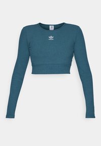 Tyrkysový žebrovaný dlouhý rukáv cropped top s kulatým výstřihem a bílým logem Adidas umístěným pod límcem.