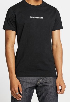 Zwart katoenen T-shirt met een wit gedrukt logo "CALVIN KLEIN JEANS" op de borst, korte mouwen en een ronde hals.