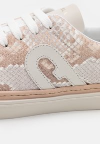 Sneakers in pelle sintetica effetto serpente beige e crema, dotati di lacci bianchi, una suola in gomma color crema e un logo ben visibile sul lato.