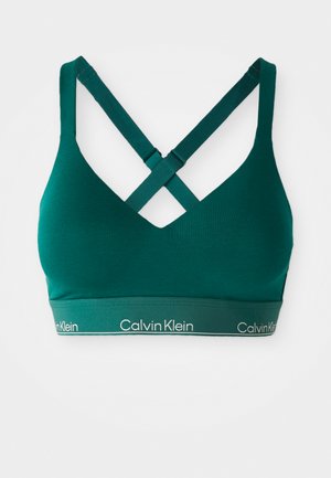 Teal sportbeha met gekruiste bandjes, gemaakt van gladde, elastische stof. Voorzien van een brede elastische band met de tekst "Calvin Klein" in het wit.