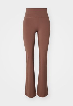 Ruskeat levenevät legginsit, jotka on valmistettu venyvästä materiaalista. Ne ovat korkeavyötäröiset ja niillä on sileä pinta, suunniteltu mukavuutta ja joustavuutta varten.