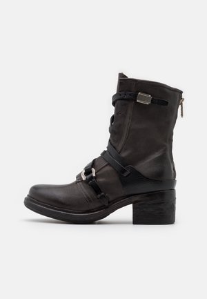 Schwarzer Leder-Stiefelette mit klobigem Absatz, ausgestattet mit Schnallen und Riemen, einem seitlichen Reißverschluss und einer strukturierten Lederapplikation.