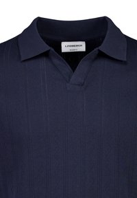 Tummansininen polo-paita, jossa on hienovaraisia pystysuoria kuvioita ja ribbikerros, merkitty Lindbergh Relaxed Fit.