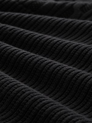 Zwart getextureerd stof met verhoogde golfpatronen. Het materiaal lijkt zacht en licht pluche, met diepe tonale variaties over het oppervlak.