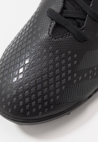 Mustat urheilukengät, joissa on teksturoitu pinta timantin kaltaisilla kuvioilla, nauhakiinnitys ja tyylikäs, matala profiili.