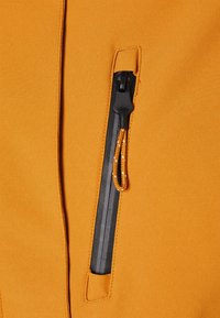 Orange stof med en glat tekstur har en lynlåslomme, der er accentueret med en sort lynlås og en orange snor.