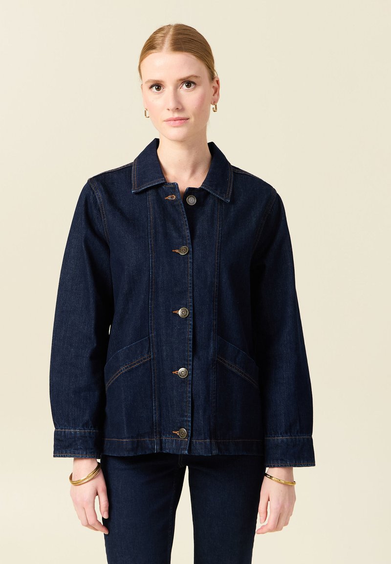 Chaqueta de mezclilla oscura con cuello con solapa, cierre frontal de botones, dos bolsillos laterales y sutiles detalles de costura.