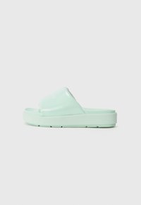 Mint green slide sandals with a glossy finish, featuring a wide strap and a textured sole for grip. Minimalist design with no additional accents.