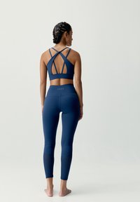 Námornícky športový top s prekríženými ramienkami a vykrojeným chrbtom, spárovaný s vysokými legínami, ktoré majú textúrované panely na lýtkach.