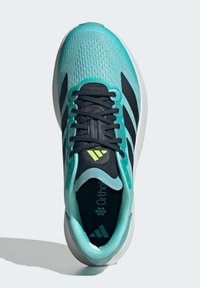 Chaussure de sport turquoise et noire avec une tige texturée, des lacets noirs et des accents verts. Elle dispose d'un col rembourré et d'une semelle intérieure matelassée.