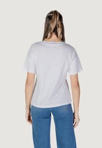 T-shirt bianco in cotone con vestibilità rilassata, maniche corte e scollatura rotonda. Presenta un piccolo etichetta del marchio sulla parte posteriore del collo.