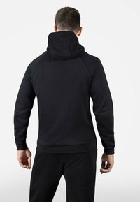 Felpa nera con alto colletto e maniche raglan. Texture liscia e polsi elastici. Design semplice senza loghi o accenti visibili.