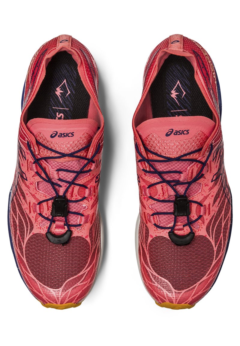 Baskets de sport rouges avec une tige en maille texturée, dotées d'un système de laçage, d'un logo et d'un design à motifs. La semelle extérieure présente des accents en caoutchouc.