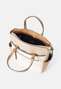 Sac à main structuré en simili cuir beige et blanc. Partie supérieure zippée, anses beige, et une poche avant avec une fermeture éclair décorative.