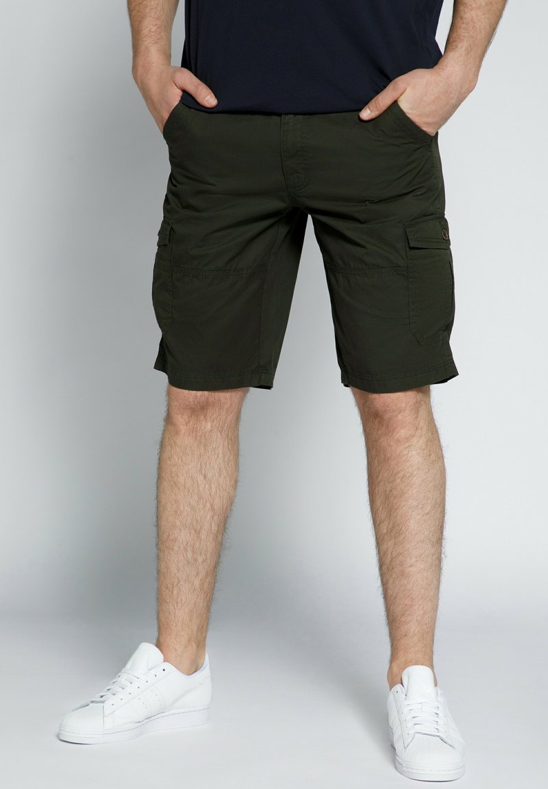 Olivenfarvede cargo shorts med flere funktionelle lommer, lavet af letvægtsstof. Båret med hvide sneakers.