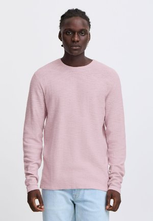 Lichtroze sweater met lange mouwen en een ronde halslijn, gemaakt van een gestructureerde stof, gecombineerd met lichtblauwe jeans. Zacht, ontspannen pasvorm en eenvoudig ontwerp.