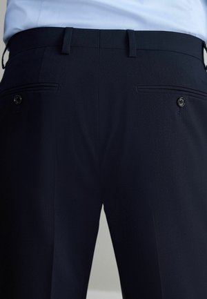 Marineblaue Hosen mit glatter Textur, ausgestattet mit zwei Gesäßtaschen mit Paspelierungen und einem Knopfverschluss, maßgeschneidert für eine figurbetonte Passform.