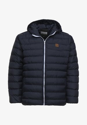Doudoune marine à zip sur le devant, capuche et design à panneaux cousus. Dotée d'une patch logo marron et d'une fermeture éclair blanche. Texturé doux.