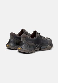 Sneakers in pelle nera e camoscio con suola spessa e testurizzata. Presentano dettagli grigi e il logo Vibram sul tallone. Design con lacci nella parte anteriore.