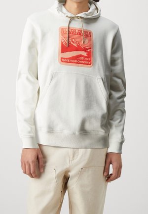 Persoon draagt een off-white hoodie met voorzak en een rood rechthoekig logo met de tekst "NAPAPIJRI" en "MAKE YOUR OWN WAY."