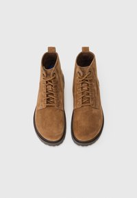 Botas de tobillo de ante marrón con cordones, puntera redonda y superficie texturizada. Cuenta con un talón reforzado y suelas de goma para un mejor agarre.