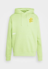 Grön bomullshoodie med känguruficka, justerbar snoddhuva och gula Nike-logodetaljer på framsidan och ärmen.