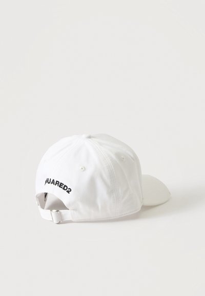 Casquette de baseball blanche avec sangle ajustable et logo partiel brodé noir "UARED2" à l'arrière, posée sur une surface blanche.