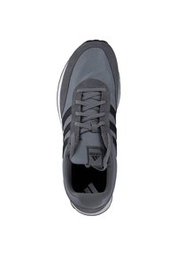 Zapato deportivo gris con parte superior de malla, tres franjas negras, cordones grises y suela de goma, con un branding mínimo en la lengüeta.
