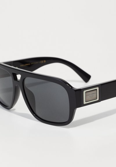 Ochelari de soare negri cu lentile întunecate, formă rectangulară și finisaj lucios. Prezentă un accent argintiu cu brandingul "DOLCE & GABBANA" pe braț.