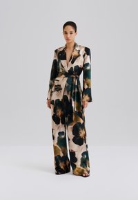 Tumma, kukkakuvioinen, silkkinen kietaisukokonaisuus, jossa on syvä pääntie, pitkät hihat ja vyötärö vyöllä. Mallissa on leveälahkeiset housut ja taskut.