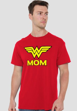 Mann trägt ein rotes T-Shirt mit einem großen gelben Wonder Woman-Logo über dem Wort "MOM" in gelbem Text.