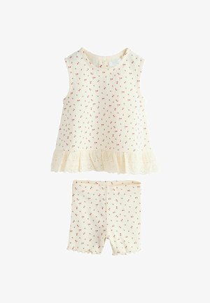 Helevalge kreemjas kaheosaline komplekt, mis sisaldab varrukateta toppi punase kirsi trükiga ja pitsäärega, ning sobivaid kirsitrükiga lühikesi pükse.