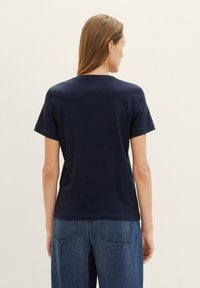 T-shirt en coton bleu marine avec des manches courtes, un col rond et une coupe décontractée. Design remarquable incluant un dos sans couture et sans étiquettes visibles.