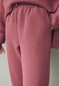 Ludd-texturerade, rosa sweatpants med elastisk midja, dragsko och sidofickor. Slätt tyg med en avslappnad passform.