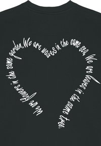 Czarna bluza z kapturem z białym, sercowatym wzorem tekstowym. Tekst zawiera frazy o jedności i wolności, w zabawnym, odręcznym stylu.