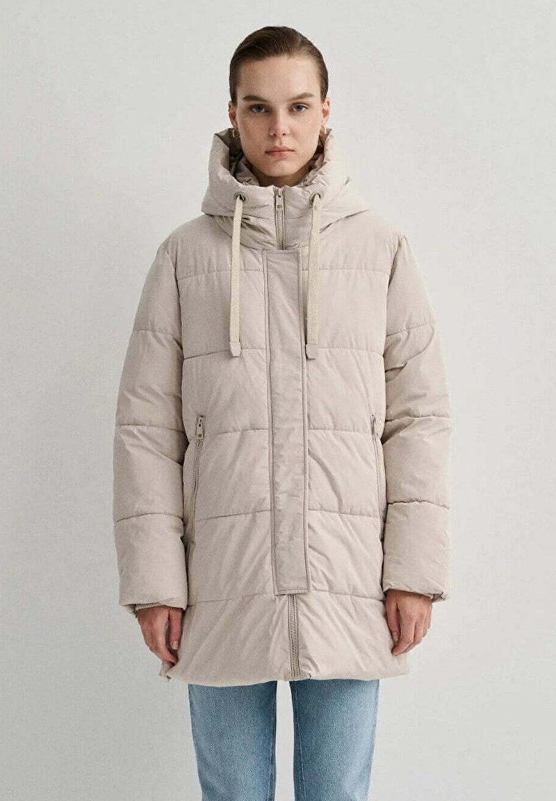 Cappotto imbottito beige con cappuccio, caratterizzato da motivi a trapunta verticali e orizzontali, chiusura anteriore con zip e dettagli con cordino.