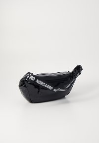 Juodas nailoninis fanny pack'as su blizgiu paviršiumi. Turi užtrauktuku uždaromą pagrindinį skyrių ir baltą logotipo diržą patogiam dėvėjimui. Minimalistinis dizainas.