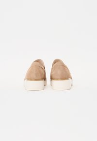 Beeg suede tossud valge kummitaldaga, tagantvaade, kus on nähtav kõver konts ja minimaalne õmbluste detail. Siledat tekstuuri, kaasaegne disain.