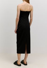 Schwarzes trägerloses Midikleid mit tailliertem Oberteil und einem Reißverschluss hinten. Verfügt über einen seitlichen Schlitz für mehr Bewegungsfreiheit und glattes, elegantes Material.