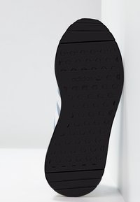 Svart gummisula med hexagonmönster, med ljusblå och vita ränder längs sidan, märkt med "adidas" nära hälen.