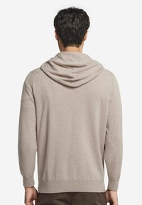 Helles beiges Kapuzensweatshirt aus weichem Material. Verfügt über gerippte Bündchen und Saum, hat eine lässige Passform und eine verstellbare Kapuze.