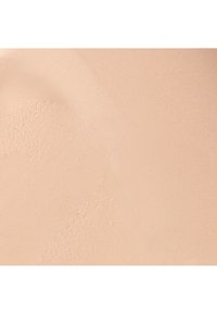 Fond de teint beige avec une texture lisse et mate. La surface présente des variations subtiles, reflétant une consistance légère et crémeuse.