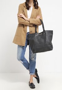 Černá kožená taška přes rameno s texturovaným povrchem, dvojitými uchy a zlatými akcenty. Prostorný design vhodný pro každodenní použití.