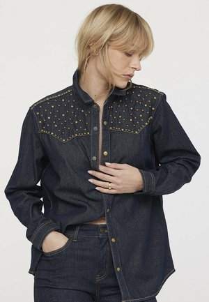 Chemise en denim foncé à boutons avec un design à clous sur les épaules, à coupe décontractée et à manches longues. Accents en métal doré.