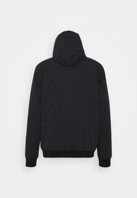 Sort hættejakke med mat finish, elastiske manchetter og kant. Har et sømløst bagdesign uden synligt hardware eller mønstre.