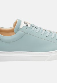 Sneaker in pelle azzurra chiara con una superficie liscia, dotata di suola in gomma bianca, lacci coordinati e un'etichetta sulla linguetta.