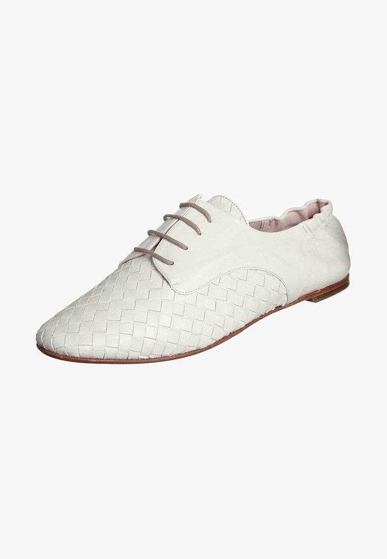 Chaussure blanche en cuir tressé à lacets avec bout pointu et semelle plate marron.