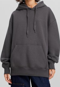 Mörkgrå huvtröja med en rymlig passform, dragsko i huven, framficka och ribbade ärmslut samt nederkant. Mjuk tygtextur.