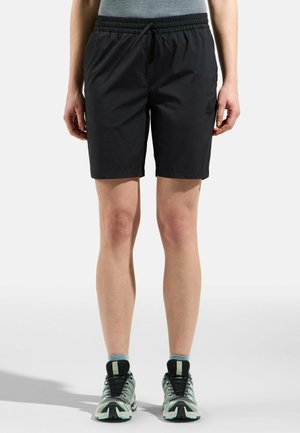 Schwarze Sportshorts mit einem elastischen Bund, Kordelzugdetails und Seitentaschen; kombiniert mit mehrfarbigen Sneakers und Knöchelsocken.
